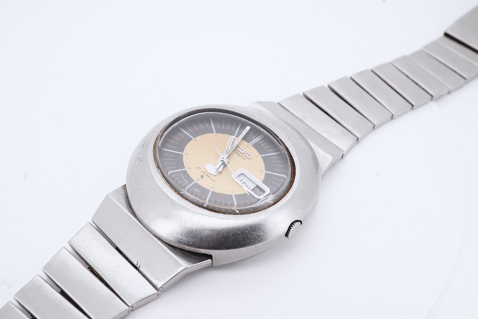 A gentleman's steel Seiko 5 Automatic wrist watch, with oval dial, baton numerals and date aperture, case diameter 40mm, case back numbered 228258, on a stainless steel Seiko bracelet(a.f.), no box or papers. Condition -